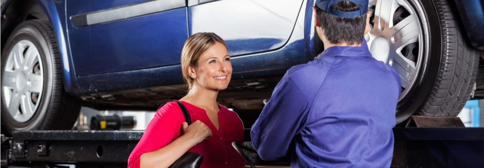 Woman smiling at technician performing car tire maintenance